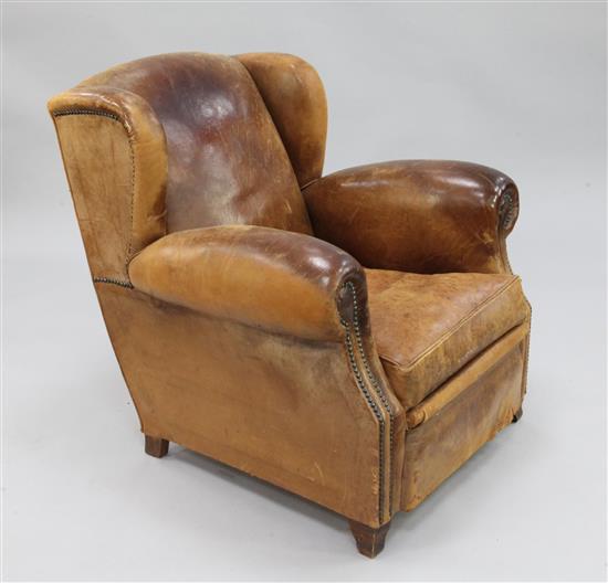A 1930s brown leather wingback armchair,